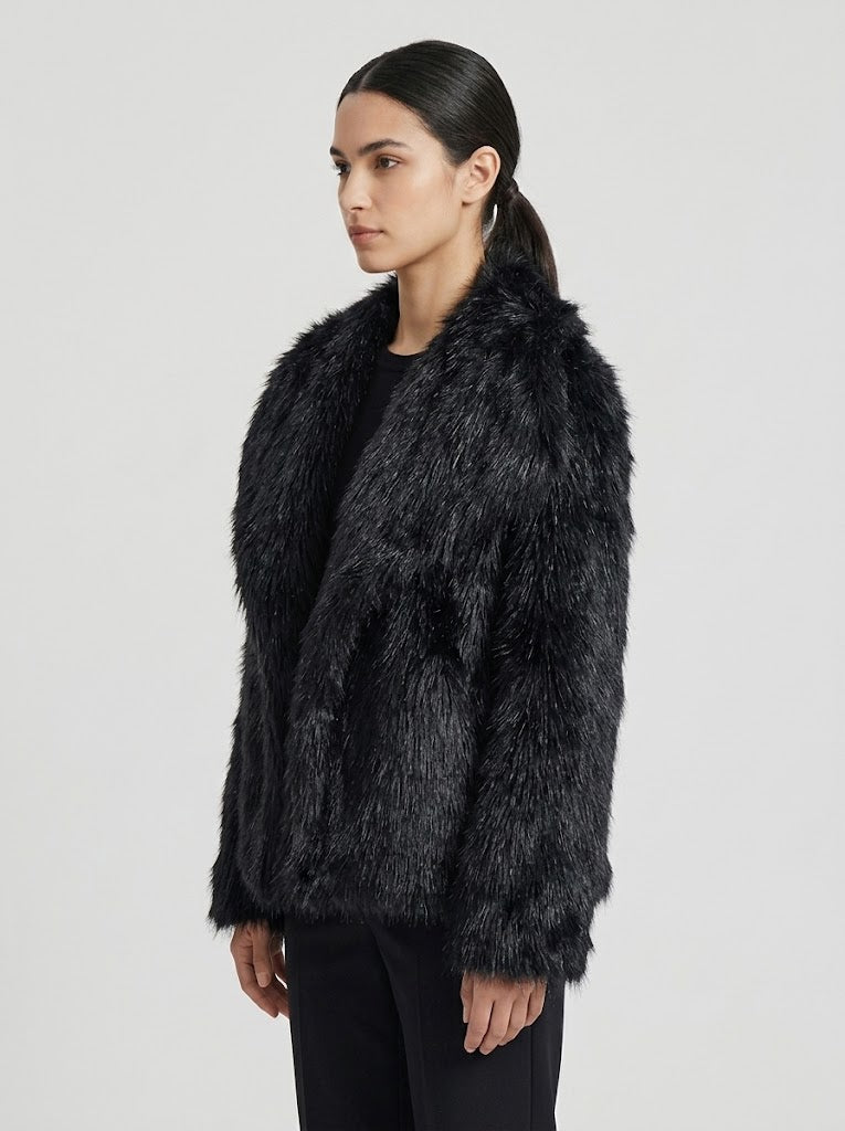 A woman modeling a black faux fur jacket against a light gray studio background.