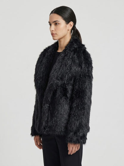 A woman modeling a black faux fur jacket against a light gray studio background.