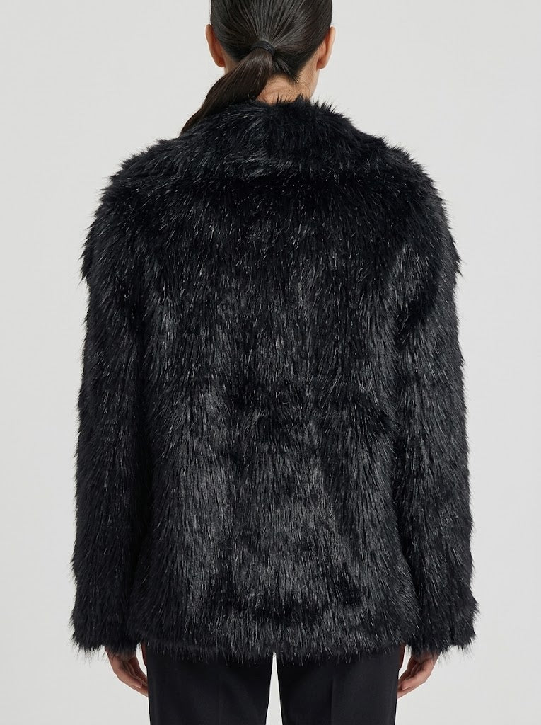 A model viewed from the back wearing a black shaggy faux fur jacket against a light gray studio background.